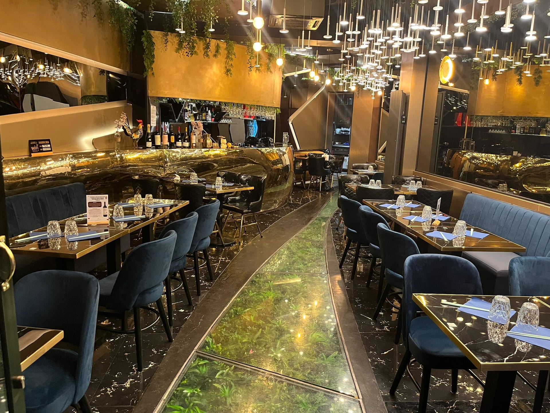 Bar doré sculpté du restaurant Phở 98 surmonté de suspensions cristal